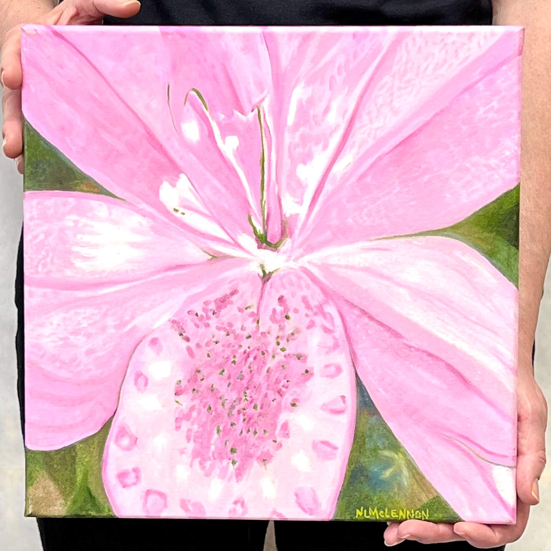 A painting, by fine artist Nancy McLennon, of light pink lily in a green garden background being held by artist