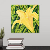 A painting, by fine artist Nancy McLennon, of a single yellow lily in a green garden hanging over a desk