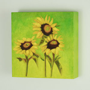 a painting by fine artist Nancy McLennon of a trio of yellow sunflowers and leaves on a warm green to yellow background sideview