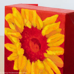a painting by fine artist Nancy McLennon of a yellow sunflower with a red center on a red ombre background detail