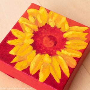 a painting by fine artist Nancy McLennon of a yellow sunflower with a red center on a red ombre background overview