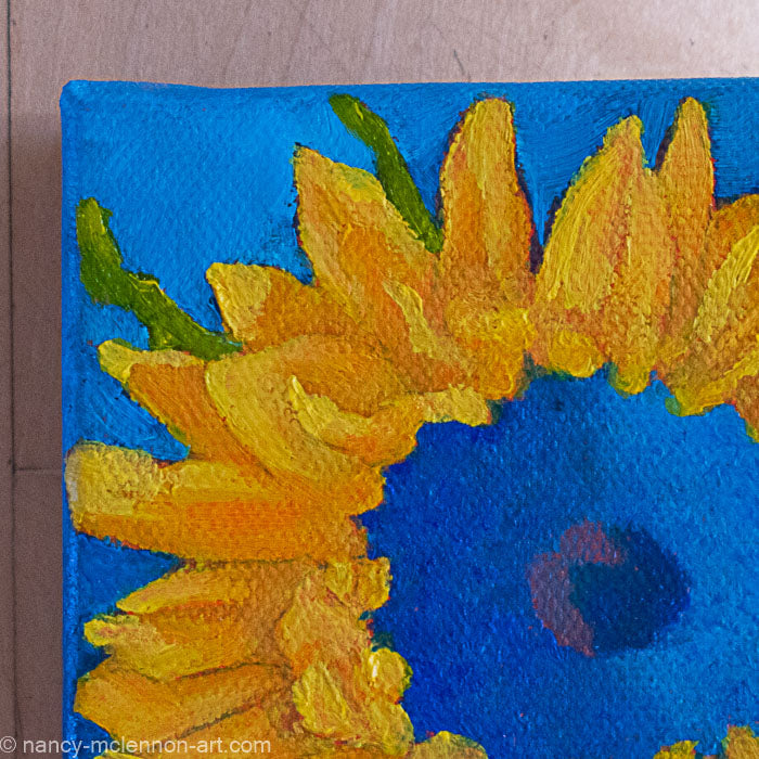 a painting by fine artist Nancy McLennon of a yellow sunflower with a blue center on dark blue background detail