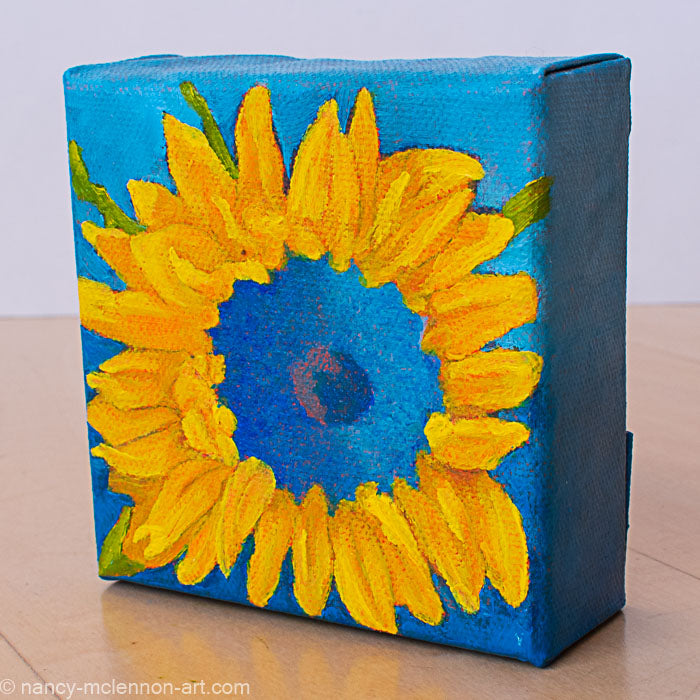 a painting by fine artist Nancy McLennon of a yellow sunflower with a blue center on dark blue background sideview