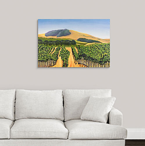 A painting of green and golden, sunlit vineyard hillsides of Napa Valley, California in the fall hanging on a white wall over a white couch