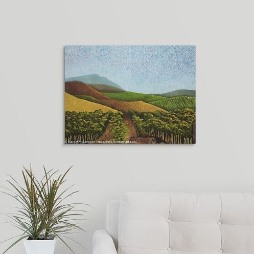 A painting of green and golden, sunlit vineyard hillsides of Napa Valley, California in the fall over a white couch